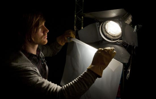 Grip working with lights on film production